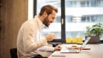 uploads - Jornal_das_Oficinas_EstudoPSE_man-holding-teacup-infront-of-laptop-on-top-of-table-inside-925786